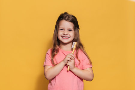 A happy girl is holding a toothbrush in her hands. An isolated shot. Pediatric dentistryの写真素材