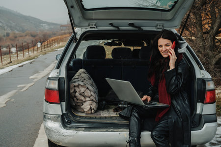 A young freelance girl works with a laptop and a phone in a car on a fresh waterの写真素材