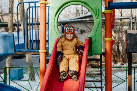 A cheerful child plays on the Playground on a snowy winter day.の写真素材