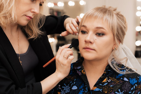Make-up artist use brush to apply blush to the skin of the modelの写真素材