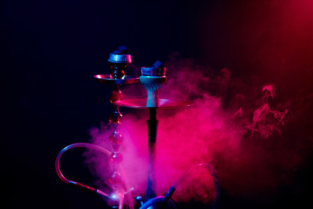 hookah bowl, shisha and coals on a smoky black background with colored lightingの写真素材