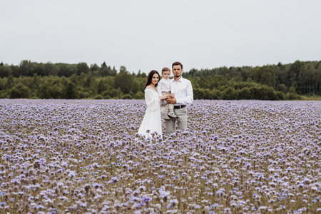 Beautiful young family with a boy resting in a field of flowers.の写真素材