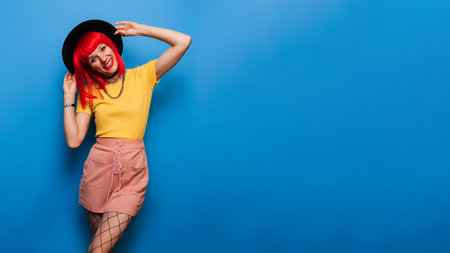 A young woman with red hair poses on a bright blue background. A studio shot. Copying the space.の写真素材