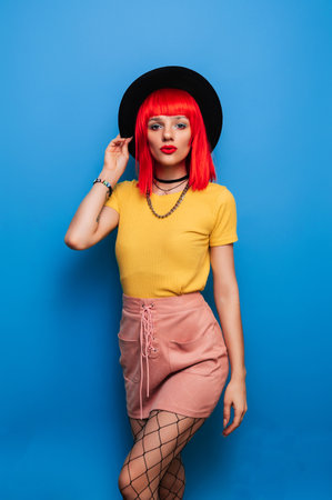 A young woman with red hair poses on a bright blue background. A studio shot.の写真素材