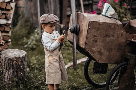 A young aviator boy near a homemade airplane in a natural landscape to fix a propeller with a wrench . Gives the picture an authentic mood. Vintage.の写真素材