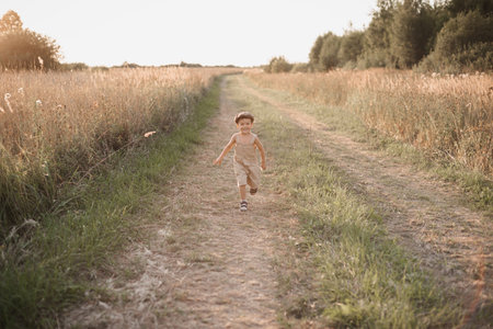 A happy child boy spends his day actively in the field in the village on a warm summer day. An authentic snapshot of childhood in the countryside.の写真素材