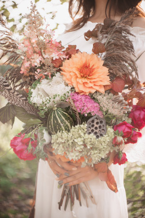 A beautiful woman holds a bouquet of flowers and herbs in her hands. Romantic moodの写真素材