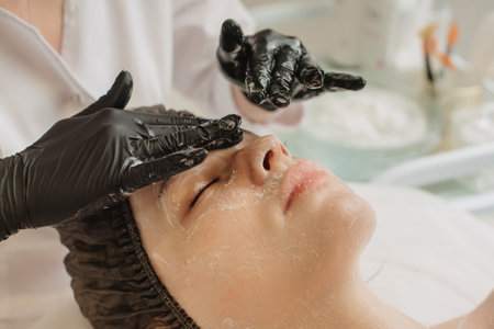 Facial peeling, spa treatments, skin care. A woman receiving facials from a cosmetologist at a spa, close-up.の写真素材