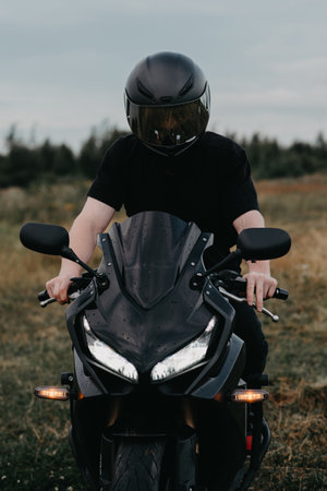 A motorcycle driver wearing a helmet is sitting on a sports motorcycle.の写真素材