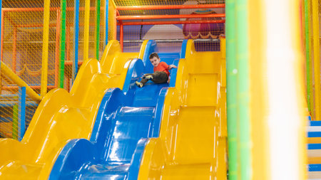A boy rides from the childrens slides on the playground in the play center. Active leisure. Childhood and joy.の写真素材