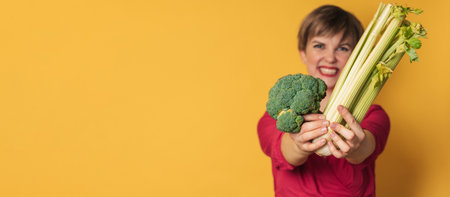 Smiling slender Caucasian girl with green vegetables in her hands, broccoli and celery, free space. Organic vegetables.の写真素材