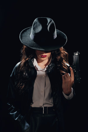 Close-up portrait of a female detective in a coat and hat with a gun in her hands. A book drama noir portrait in the style of detectives of the 1950s.の写真素材