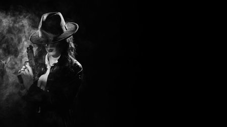 Silhouette: a female detective in a coat and hat with a gun in her hands. Dramatic noir portrait in the style of books and detective films of the 1950s. black and white snapshotの写真素材