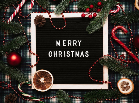 Merry Christmas lettering in plastic letters on an letter board.There are caramel canes, balls,cones and fir branches and dried orange all around.Top view.Flatley.Christmas greeting card.の写真素材