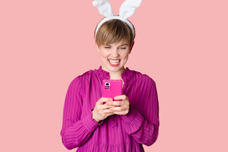 A beautiful girl with bunny ears on a colored background with a smartphone in her hands.の写真素材