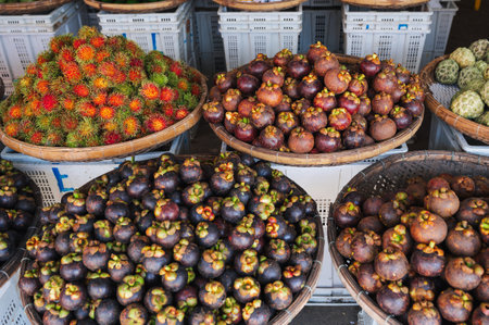 Mangosteen and rambutan are sold in wicker baskets in the Asian marketの写真素材