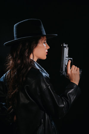 Silhouette of a female detective in a coat and hat with a gun in her hands. A book drama noir portrait in the style of detectives of the 1950s.の写真素材