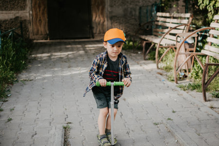 A little boy rides a scooter outdoors in an urban environment.の写真素材