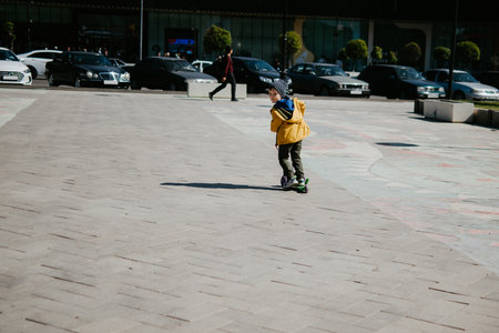 A little boy rides a scooter outdoors in an urban environment.の写真素材
