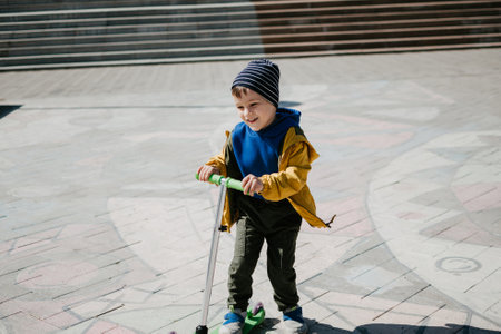 A little boy rides a scooter outdoors in an urban environment.の写真素材