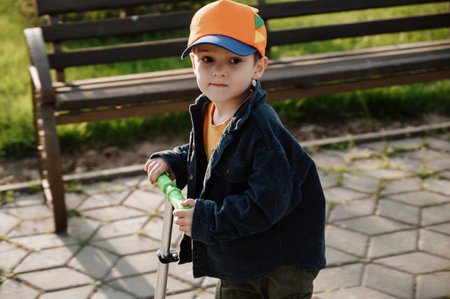 A little boy rides a scooter outdoors in an urban environment.の写真素材
