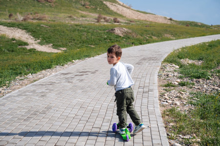 A little boy rides a scooter outdoors in a parkの写真素材