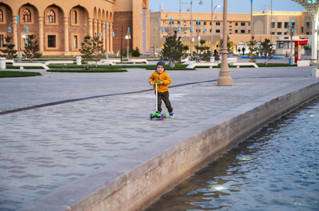 A little boy rides a scooter outdoors in an urban environment.の写真素材