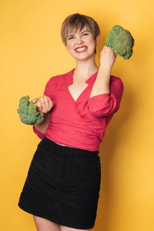In the studio shot, a young Caucasian woman holds fresh broccoli in her hands. of the healthy eating concept.の写真素材