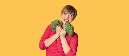 In the studio shot, a young Caucasian woman holds fresh broccoli in her hands. of the healthy eating concept. A place for your text. Panoramic banner.の写真素材