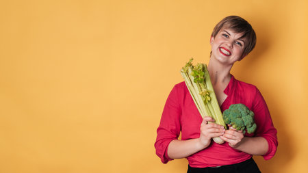 Smiling slender Caucasian girl with green vegetables in her hands, broccoli and celery, free space. Organic vegetables.の写真素材