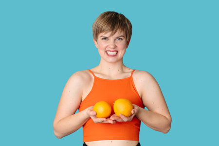 Smiling slender Caucasian girl with citrus oranges in her hands. Vitamin C.の写真素材