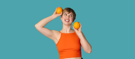 Smiling slender Caucasian girl with citrus oranges in her hands. Panoramic banner, free space. Vitamin C.の写真素材