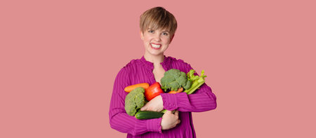 Studio shot, a young Caucasian woman holding a lot of fresh vegetables in her hands. The concept of healthy eating. Vegetarianism. A panoramic banner with a copy of the space.の写真素材