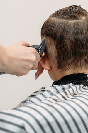 A female hairdresser cuts a little boys hair with a hair trimmer.の写真素材