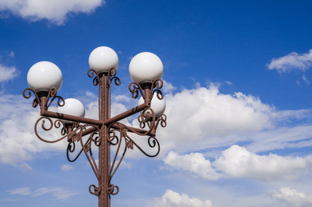 A classic street lamp with white globes under a clear blue sky, adding charm to any urban landscape.の写真素材