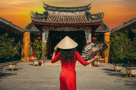 A woman in a traditional Vietnamese dress on the background of an Asian temple in Hoi Anの写真素材