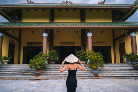 Chua Linh Ung in Da Nang, Vietnam. A female tourist wearing a traditional Vietnamese Non La hat on the background of a pagoda.の写真素材