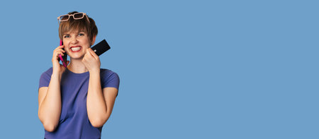 The concept of online shopping. A Caucasian young woman holds a credit card, talks on a smartphone,...