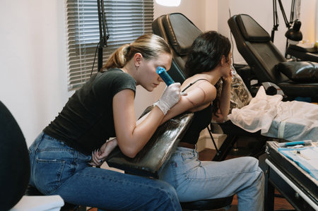 Professional female tattoo artist makes a tattoo on a womans body in the studio.の写真素材