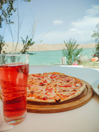 Gourmet pizza served on the wooden board on the wooden table with beach views at the background.の写真素材