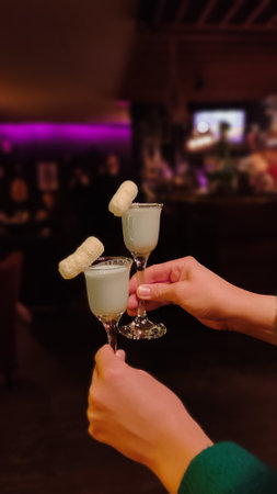 two shots of liquor in womens hands on the background of the barの写真素材