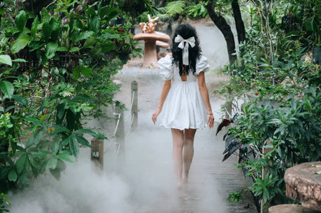 A fantasy elf woman in a white dress strolling through a fairy-tale forest with thick fog.の写真素材