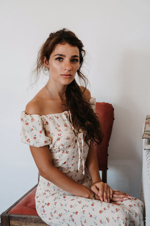 Portrait of a young woman in a vintage womens dress, sitting on vintage furniture.の写真素材
