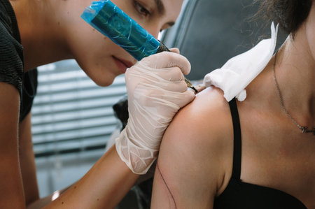 Professional female tattoo artist makes a tattoo in the studio, close-up.の写真素材