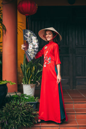A woman in a traditional Vietnamese costume, a conical hat in an ancient Asian city decorated for the Tet holidayの写真素材