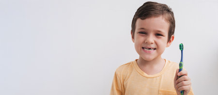Portrait of a smiling little boy without a baby tooth with a toothbrush, close-up. Panoramic banner. Oral care in children.の写真素材