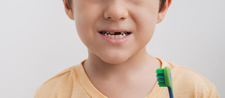 The smile of a little boy without a baby tooth with a toothbrush, close-up. Panoramic banner. Oral...