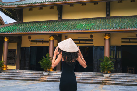 Chua Linh Ung in Da Nang, Vietnam. A female tourist wearing a traditional Vietnamese Non La hat on the background of a pagoda.の写真素材