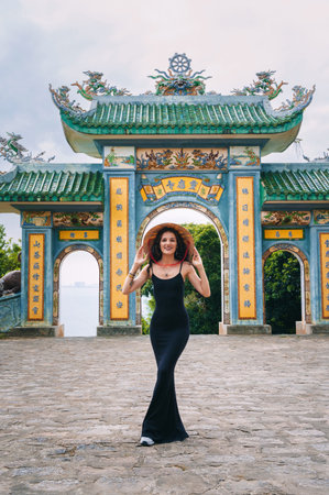 Woman traveler on the background at Linh Ung Pagoda temple. Tourist with Vietnamese hat and with a fan traveling in Da Nang city.の写真素材