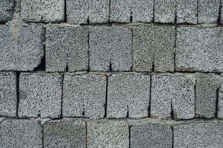 A plain gray cinder block wall with a rough, industrial texture